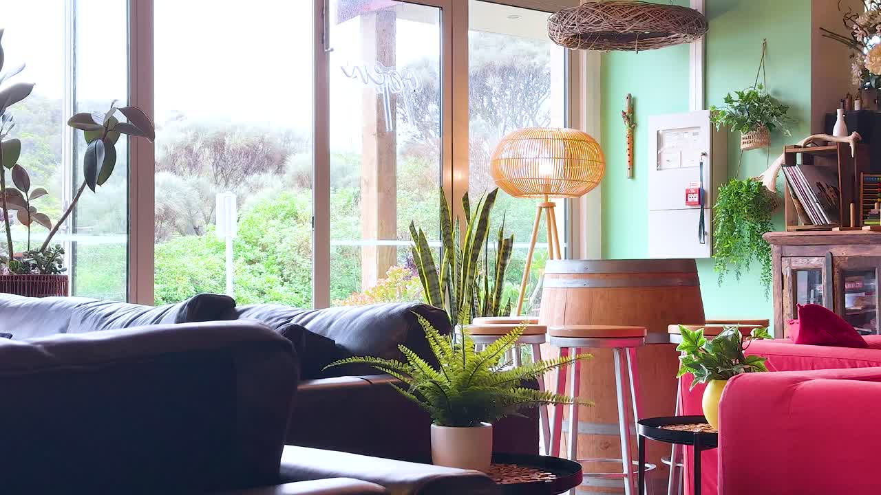 A serene living room featuring lush indoor plants, warm lighting, and large windows offering a view of greenery