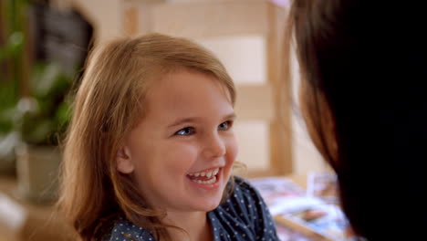 Daughter-Sitting-On-Mother's-Lap-At-Home-And-Laughing