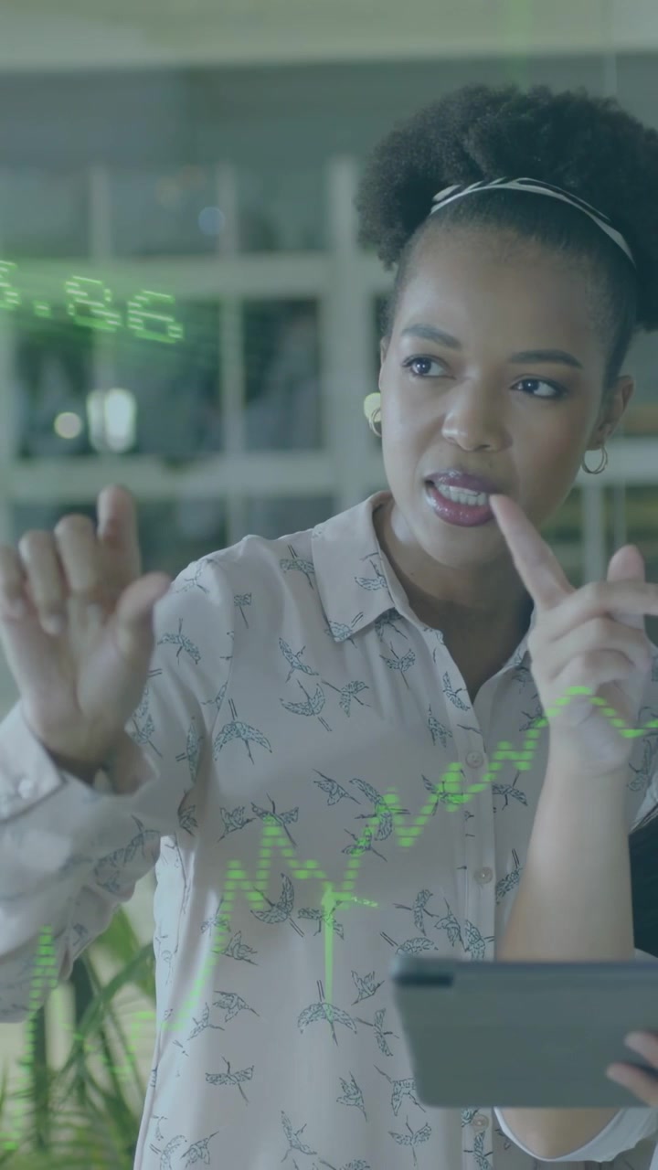Video verticale: Donna in riunione che tiene un tablet e indica un grafico verde, spiegando le tendenze di vendita.