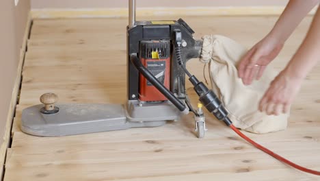 worker unplugging cord of floor sanding machine during renovation work indoors