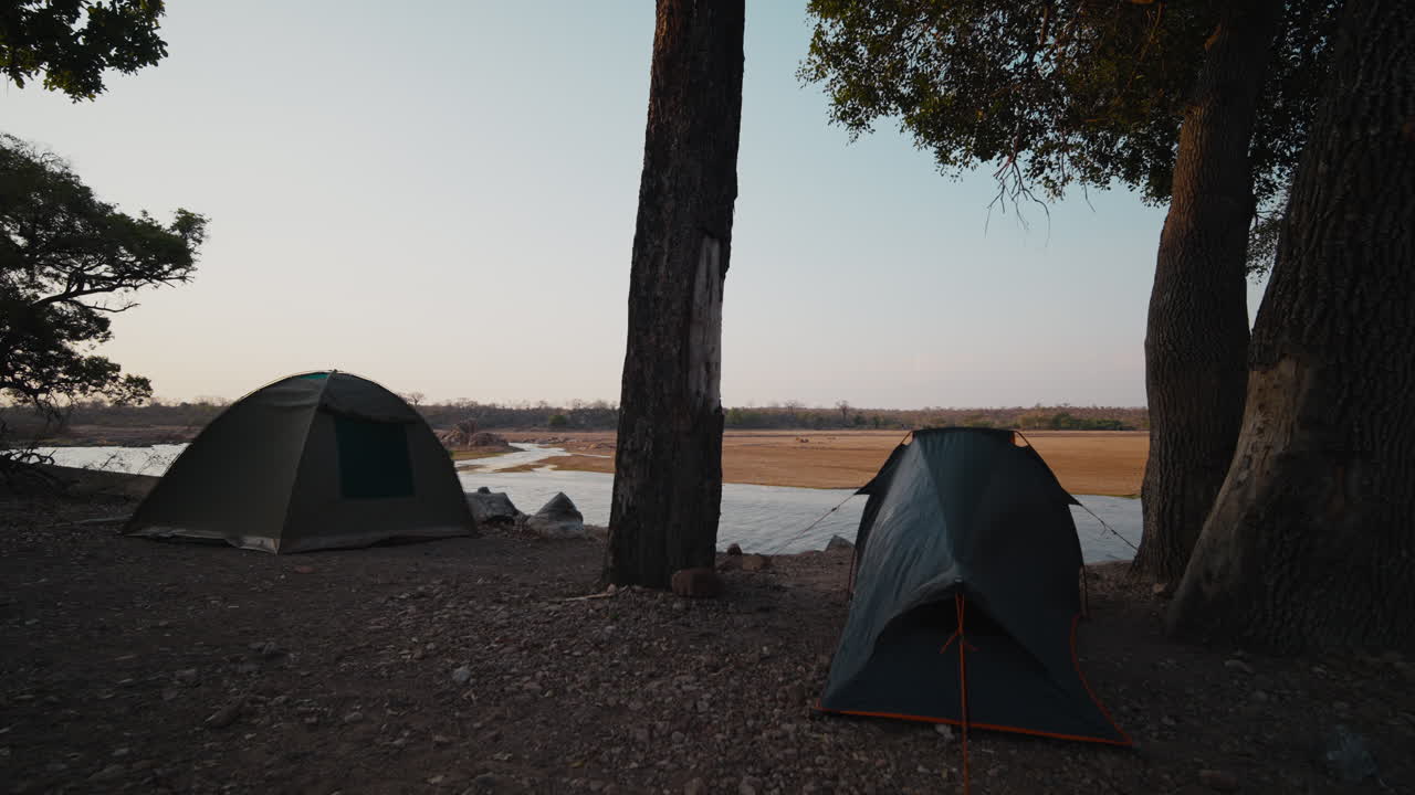 Static shot of campsite with tents overlooking the river in Gonarezhou. Natural, authentic safari setting