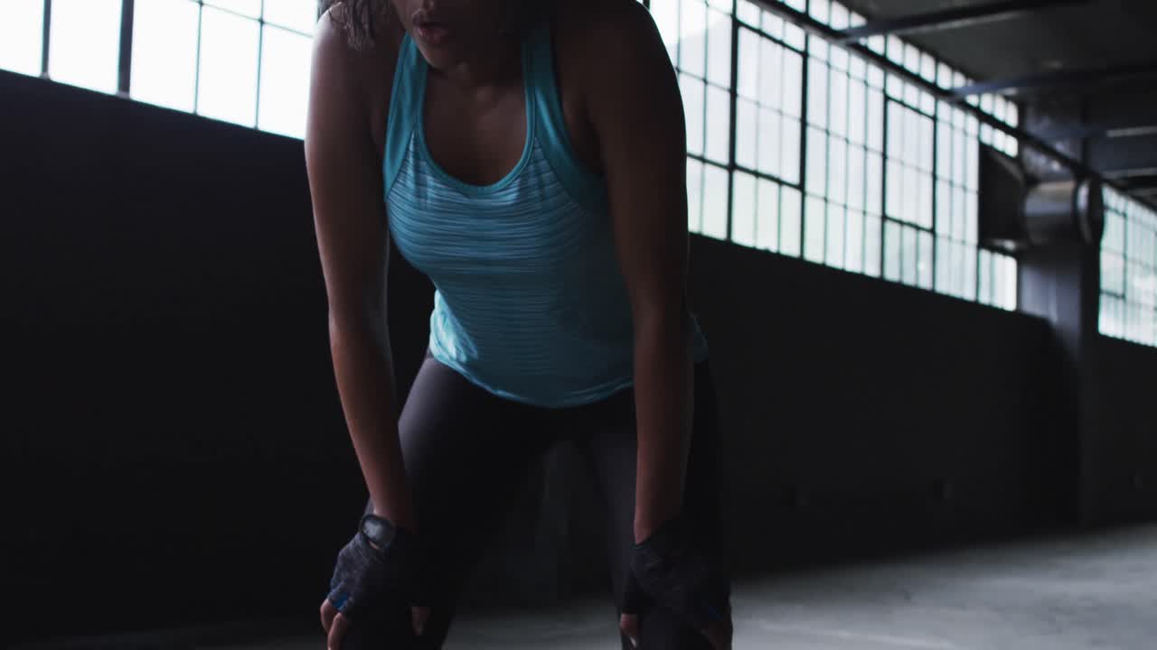 African american woman resting breathing heaviily after exercising in an empty urban building