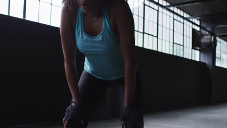 african american woman resting breathing heaviily after exercising in an empty urban building