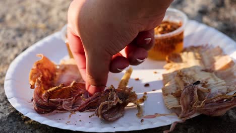 hand picking grilled food from a plate