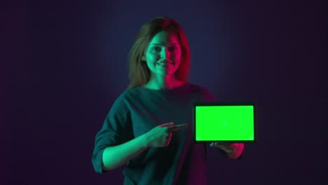 woman holding a tablet with a green screen, neon light portrait