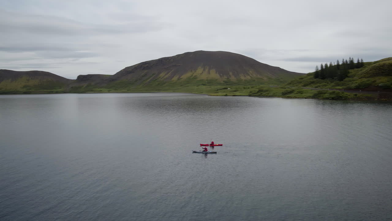 lago hestvik y paisaje orbital aéreo en islandia siguiendo dos kayaks que se mueven en sentido contrario a las agujas del reloj