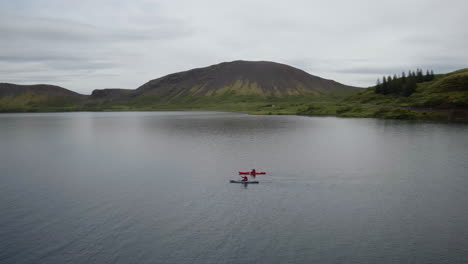 hestvik lake and landscape aerial orbital in iceland following two kayaks moving in anti-clockwise motion