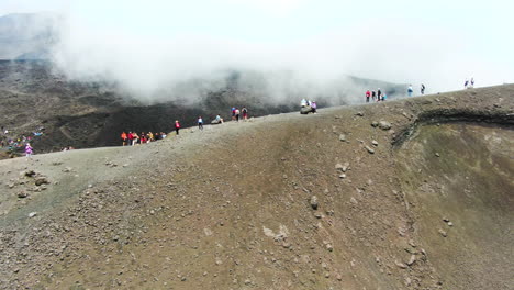 people standing on the top of torre del filosofo on etna volcano in sicily