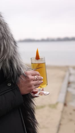 woman holding a warm drink by the lake