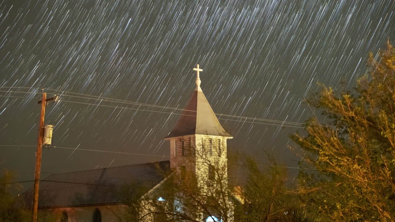Stars trail in to comets drifting upwards over a small church steeple - Astro Time lapse