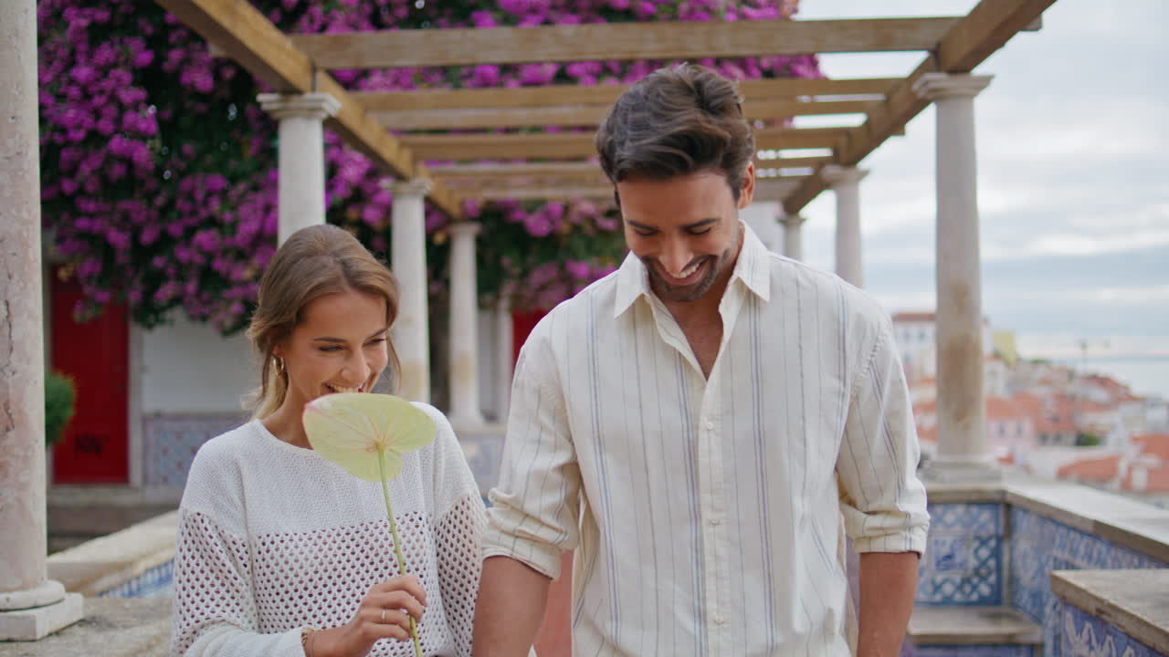 즐거운 커플이 정원에서 가까이 걸어가고 웃는 커플이 로맨틱한 데이트를 하고 있다.