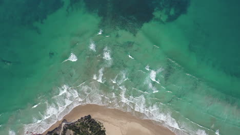 Vertical-aerial-flight-from-beach-to-coral-reef-in-shallow-green-water