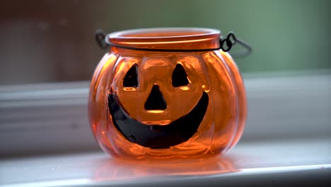 pumpkin halloween candle sitting on a white windowsill