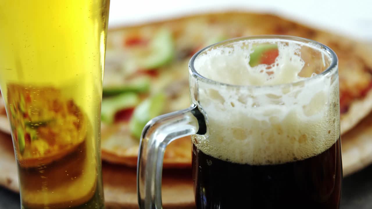 pizza deliciosa con vasos de cerveza y refrescos