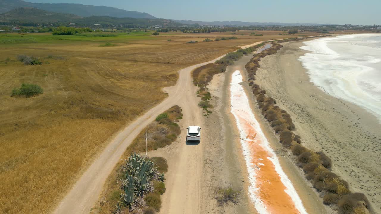 vista aérea de un coche blanco conduciendo en la carretera a lo largo de la llanura de sal de igroviotopos alikis en kos, grecia