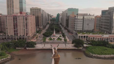 rising aerial shot behind kun iam golden statue in nape business area in macau