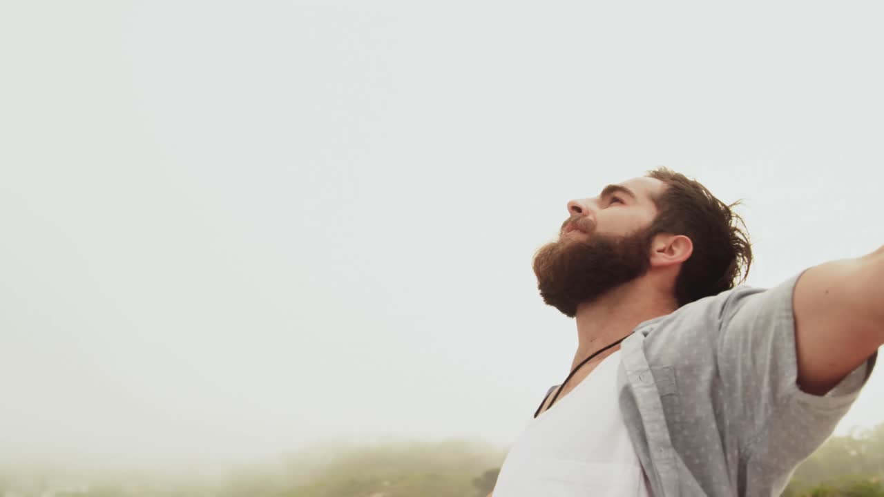 Vista laterale di un uomo caucasico in piedi con le braccia distese sulla spiaggia 4k.