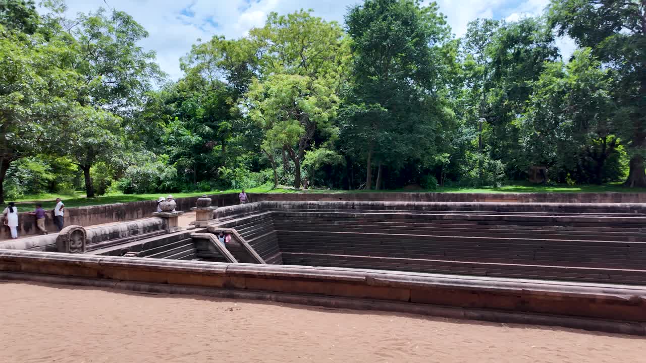 Ancient Kuttam Pokuna, or Twin Ponds, in the historic city of Anuradhapura, Sri Lanka, surrounded by lush greenery and clear blue skies.