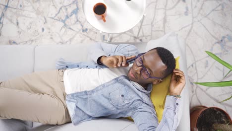 top view of young african man with glasses talking on the phone.