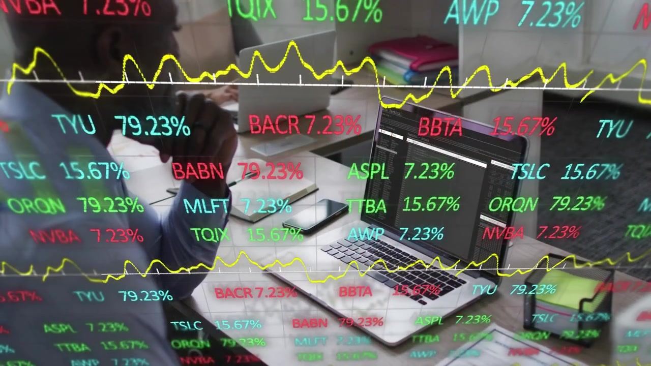 Mann lehnt sich im Büro, schaut auf den Laptop, während sich ein Ticker-Overlay aktualisiert, tippt auf sein Telefon und bereitet einen Handel vor