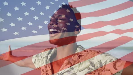 Animation-of-american-flag-waving-over-smiling-man-stretching-arms-on-beach