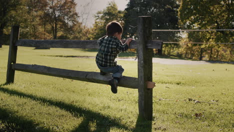 happy asian toddler running along farm fence. handheld shot