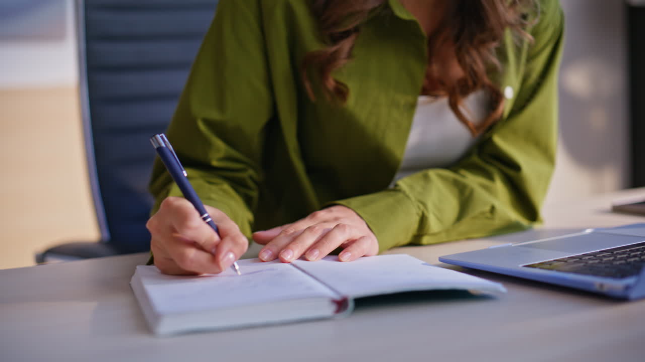 Woman writing in notebook at office desk