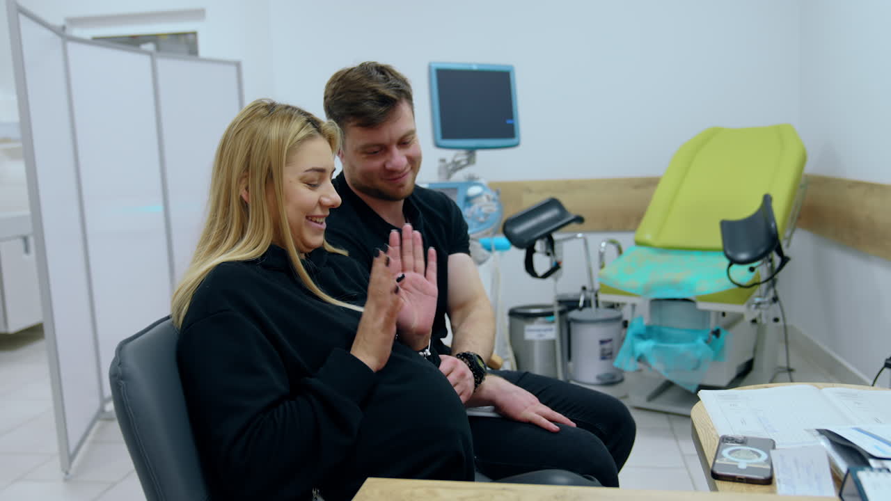 Married couple expecting a child sits at doctor's cabinet. Blonde woman with big belly is nervous before ultrasound check up.