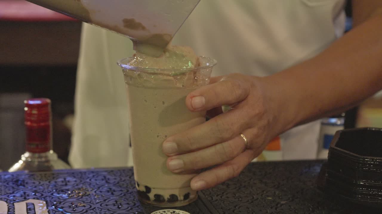 Primo piano di un barista che prepara un frullato al cioccolato con perle.