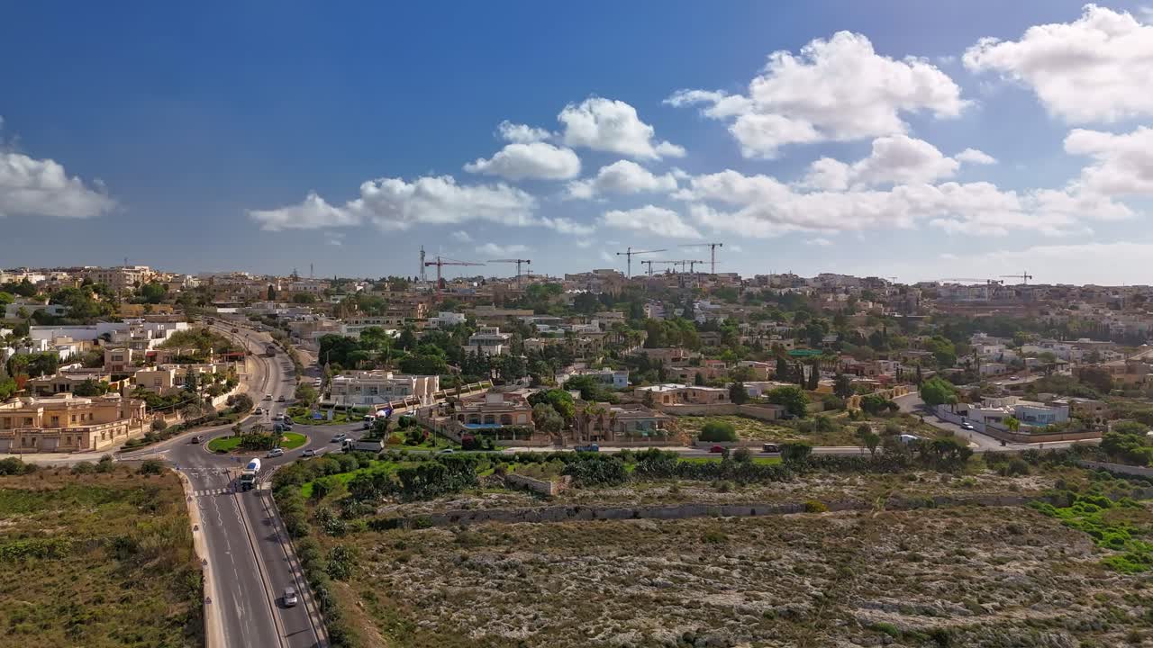 Hyperlapse realizzato con drone a Naxxar, Malta, che mostra strade trafficate, terreno calcareo e gru edili in una nuvolosa giornata autunnale