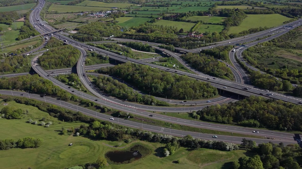 Busy Motorway Interchange Aerial Over Green Fields With Traffic Flow