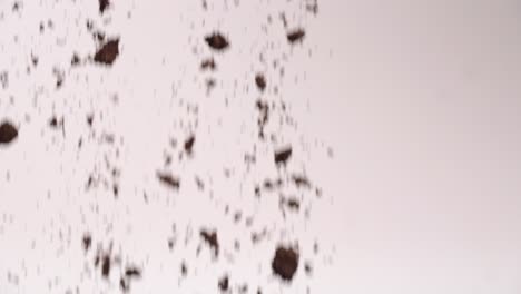 crushed sandwich cookie dirt falling in mid air in slow motion on white backdrop