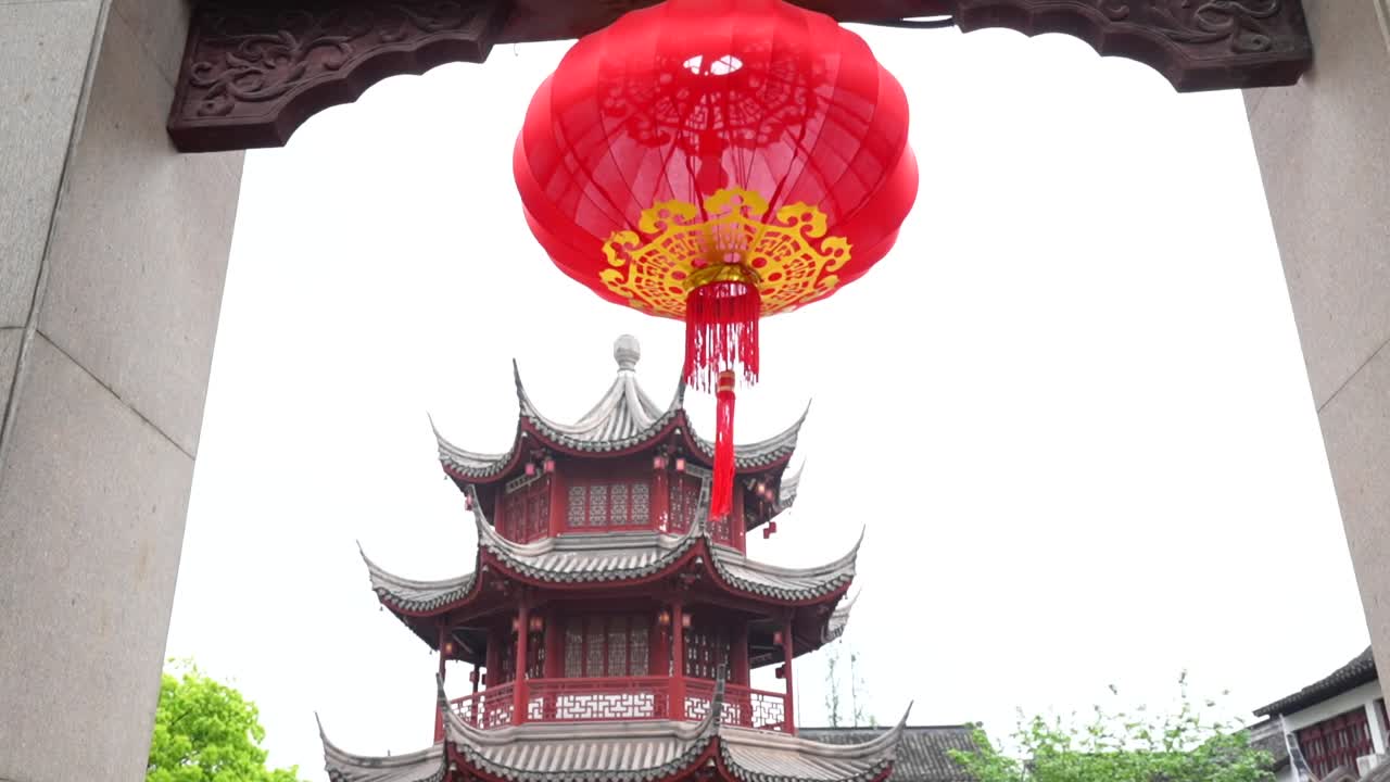 Tilt down from a red lantern at Qibao main gate to reveal a pagoda rising behind the entrance. Shanghai, China