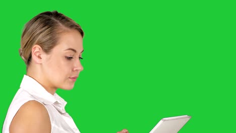 single girl walking and watching media content on line in a tablet on a green screen, chroma key