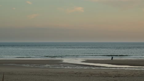 lonely man shore fishing in the golden hour at costa da caparica