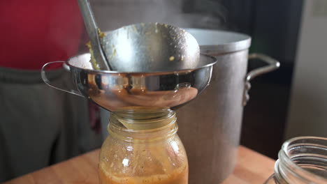 sirviendo sopa minestrone caliente en un tarro de albañil para enlatar - ángulo alto, primer plano