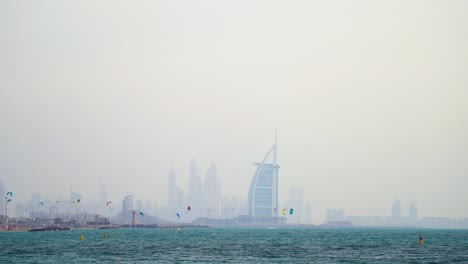 Wide-panorama-of-Dubai-skyline-including-Burj-Al-Arab-hotel-and-kite-surfers-at-Fazza-Beach