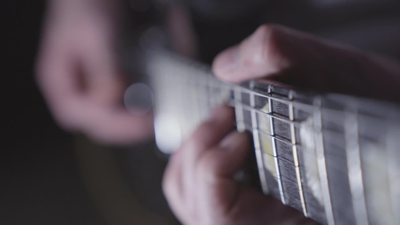Close up of person practicing riff on electric guitar. Shallow depth of field