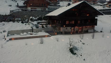 drone volando lejos de una bañera de hidromasaje de un lujoso chalet en una pequeña ciudad suiza al anochecer