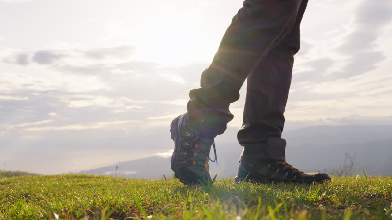 Low Angle Tracking of Hiker Standing and Walking Toward Mountain Horizon