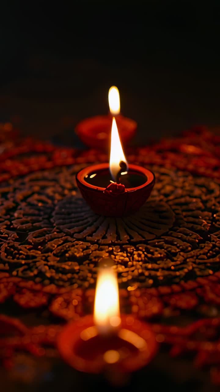 Vertical video: Central red clay oil lamp flame flickering through shifting shapes on rangoli mat
