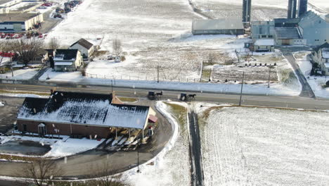 Antena-Sobre-Carruajes-Tirados-Por-Caballos-Que-Se-Mueven-A-Lo-Largo-De-La-Carretera,-Campos-Cubiertos-De-Nieve