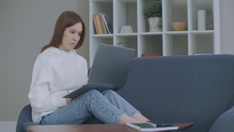 woman using laptop on couch at home. thoughtful young woman sitting with computer on couch looking outside concentrate on work feeling bored need additional motivation working remotely at home.