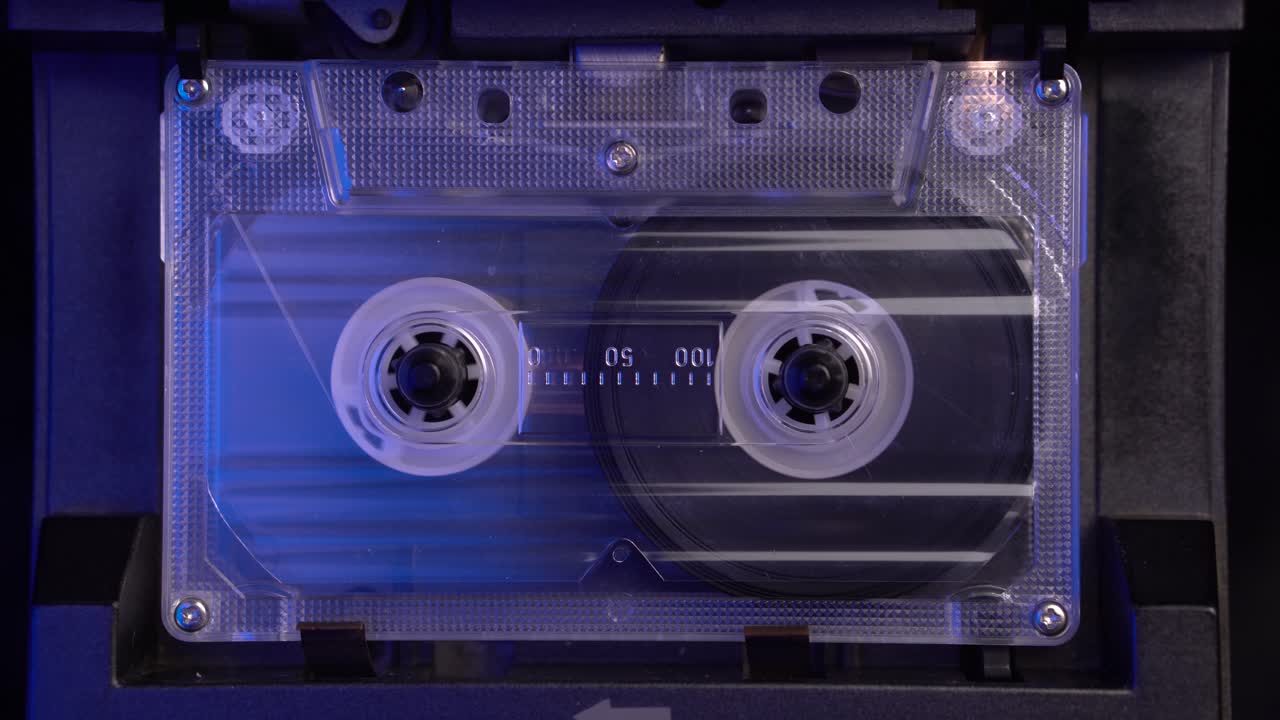 cinta de cassette de audio transparente, insertando y jugando en un reproductor de cubierta vintage de la década de 1980, de cerca