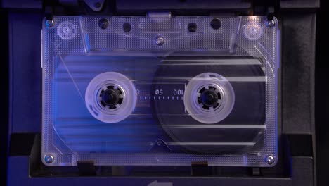 transparent audio cassette tape, inserting and playing in vintage deck player from 1980's, close up