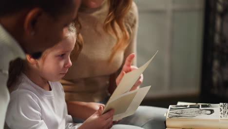 lady shows old pictures to little niece with husband at home