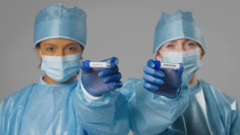 fotografía de estudio de trabajadoras de laboratorio con tubos de ensayo etiquetados como covid-19 y omicron