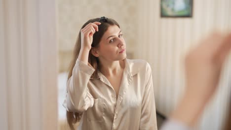 Pretty-young-woman-doing-a-roller-head-massage-in-front-of-a-mirror