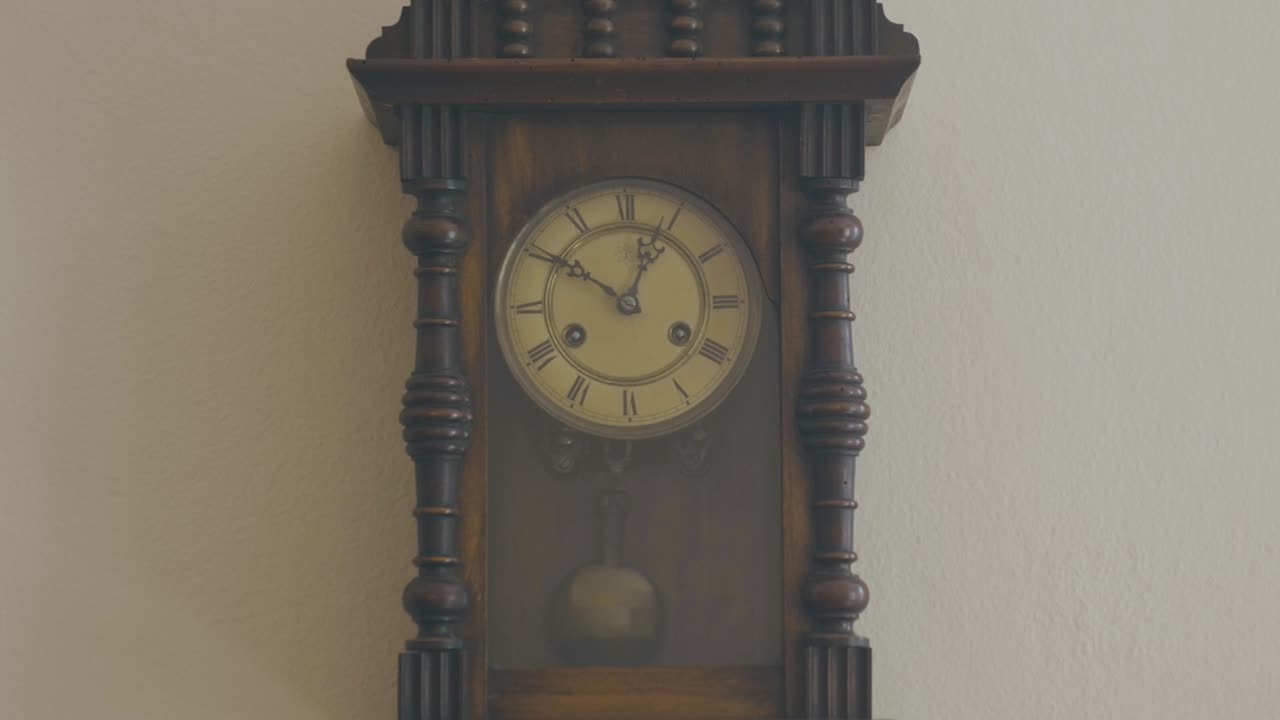 Antique grandfather clock hanging on a wall of a rose-colored house