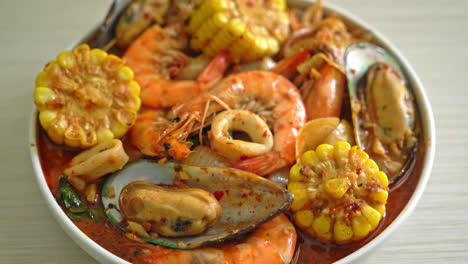 mariscos picantes a la barbacoa: gambas, calamares, mejillones y maíz.